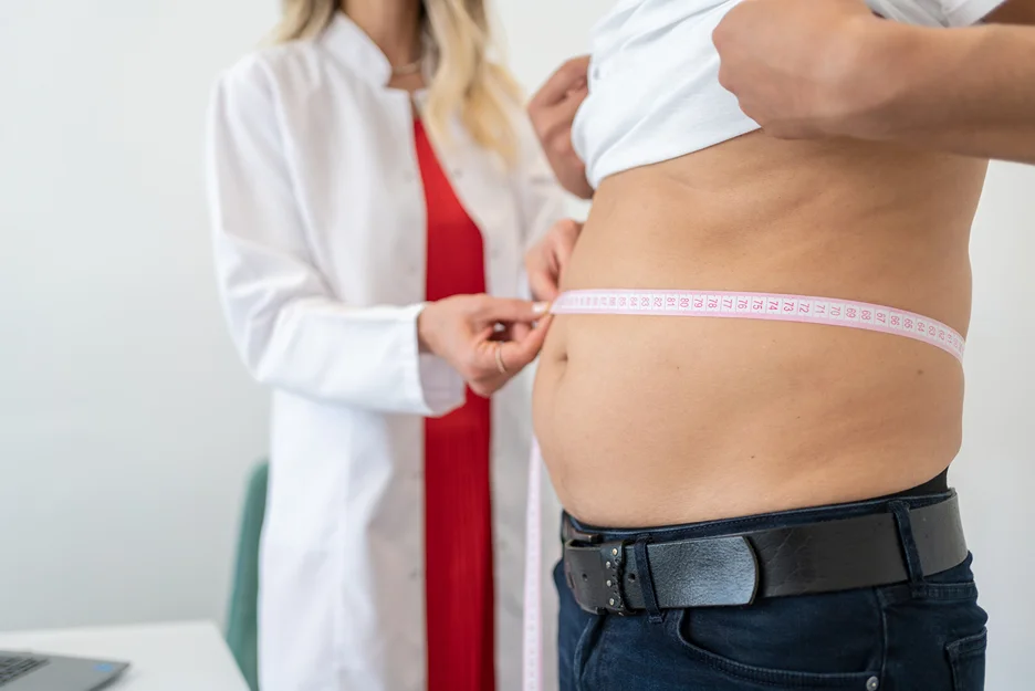 a doctor measures a male patient's waist