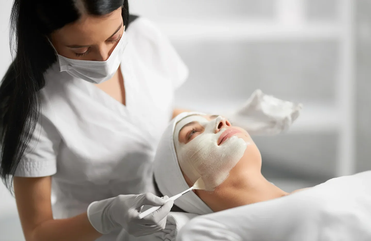 an esthetician performs facial treatment on a client