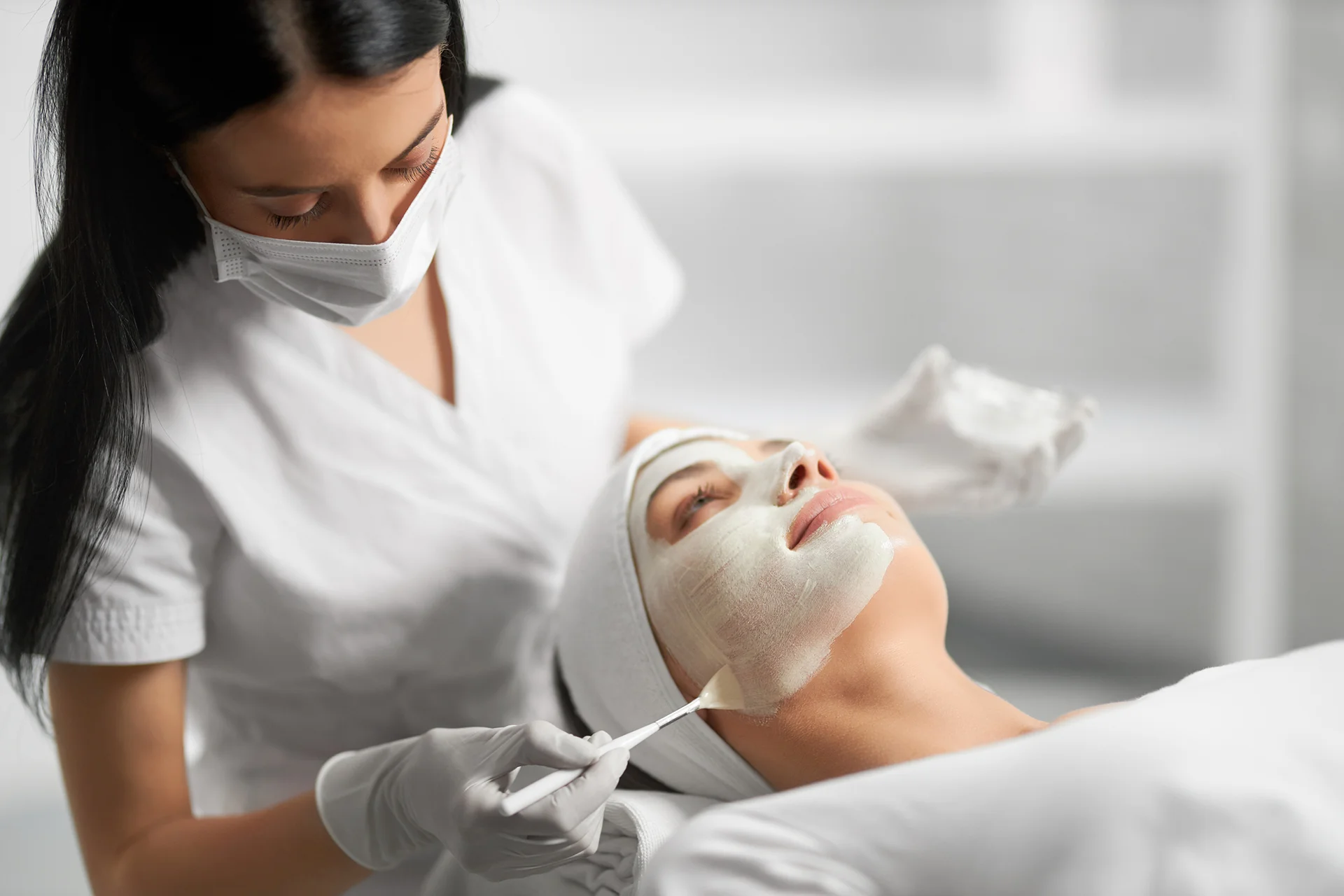 an esthetician performs facial treatment on a client