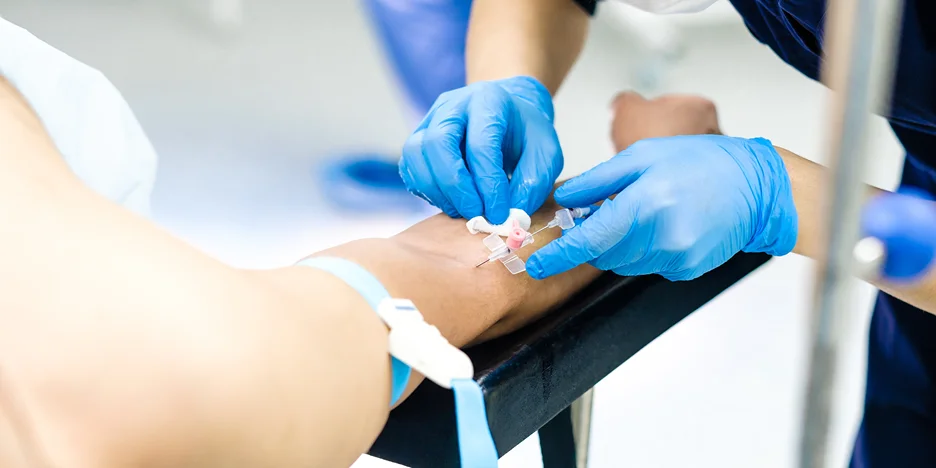 a nurse inserts butterfly needle unto the patient's arm for blood draw