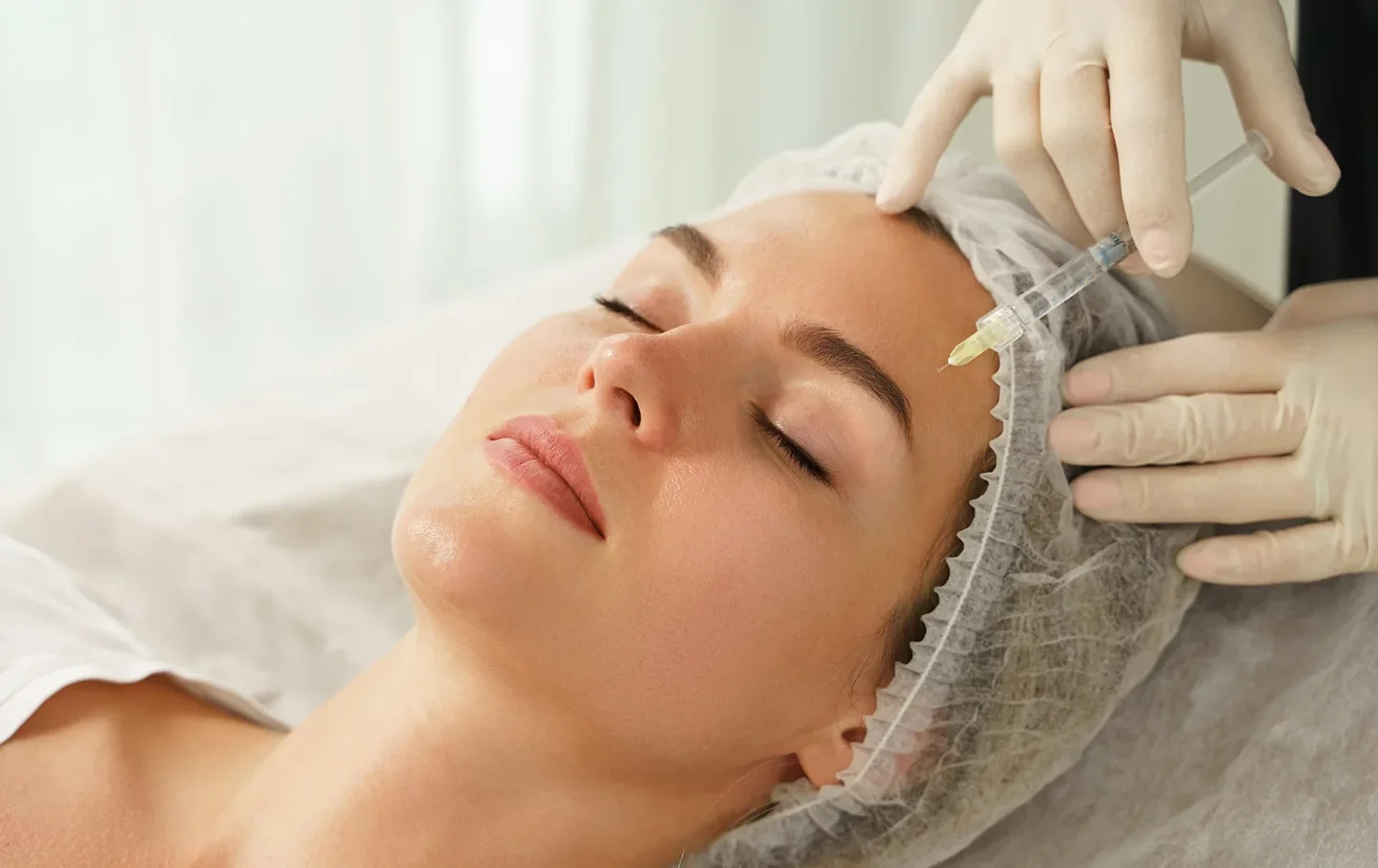 an esthetician performs botox treatment on the client