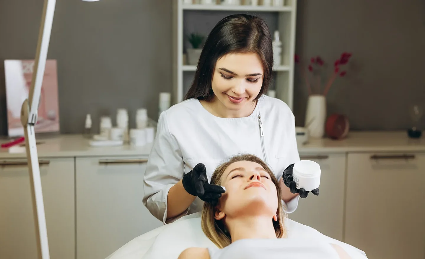 an esthetician applies moisturizer on her client's face