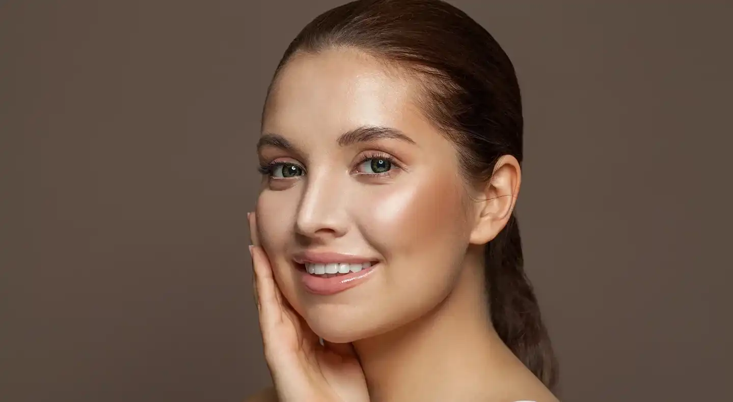 a portrait of a woman touching her glowing skin after PDRN treatment