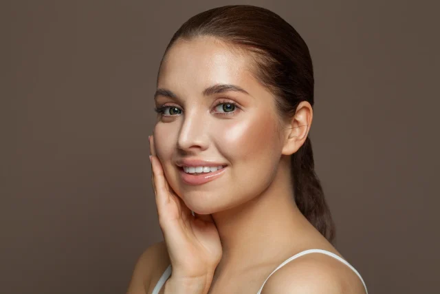 a portrait of a woman touching her glowing skin after PDRN treatment