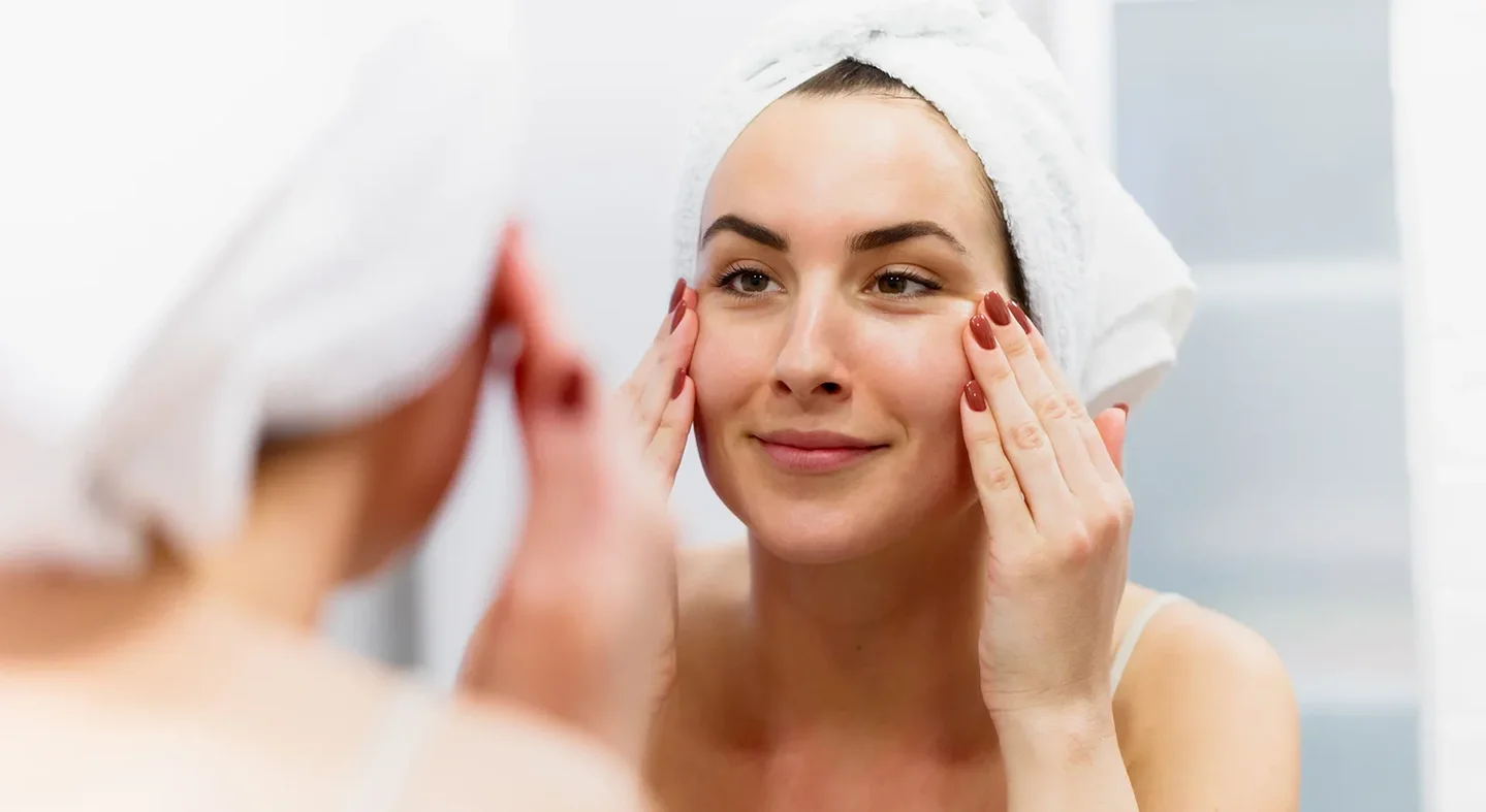 a woman checks her face in front of the mirror