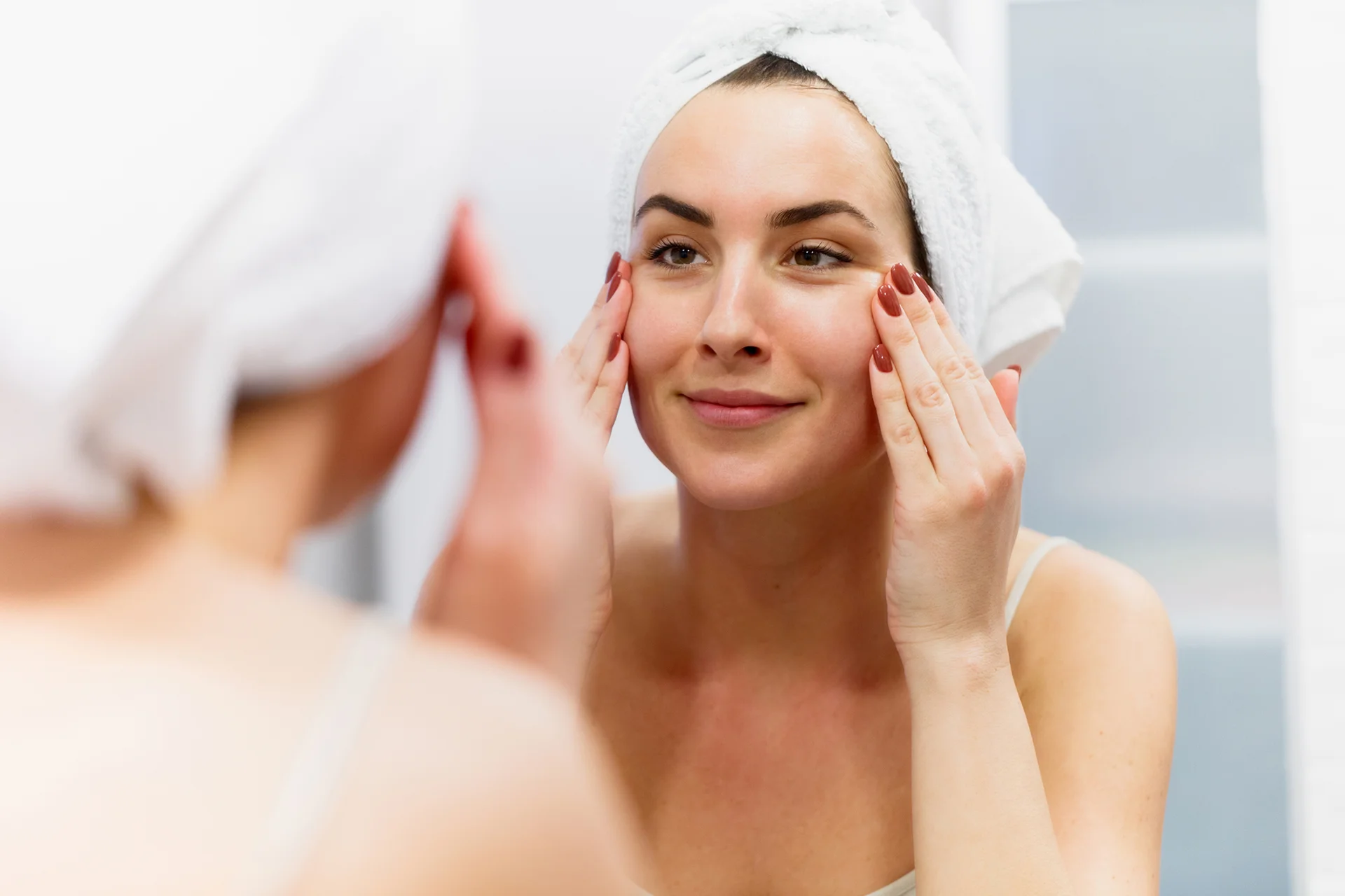 a woman checks her face in front of the mirror