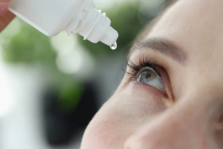 a portrait of a woman dripping into her eyes with pdrn eye drop