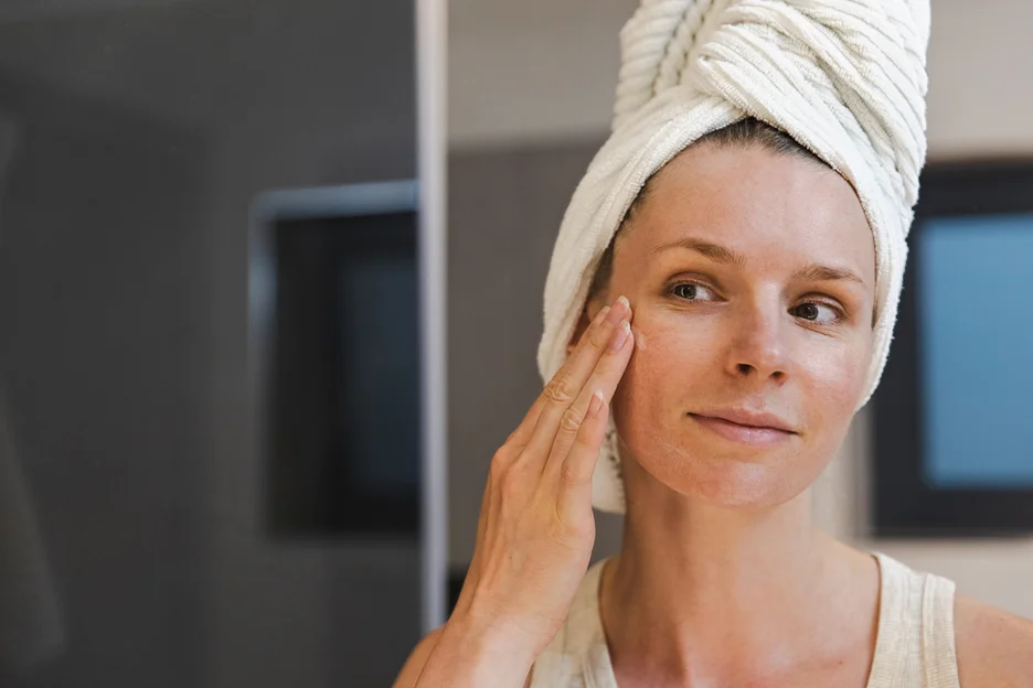 a woman applies dna salmon skincare in front of the mirror