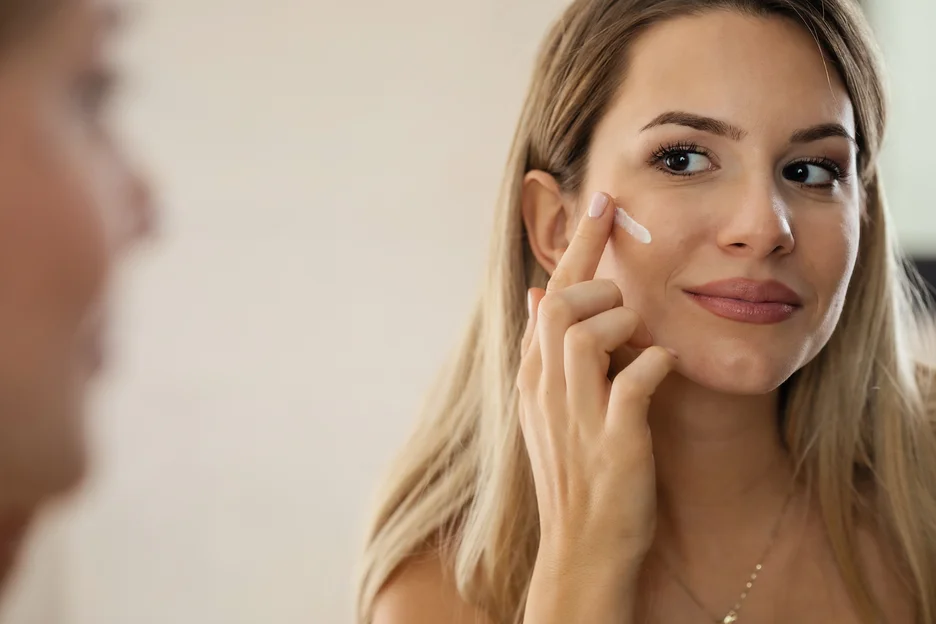 a woman applies salmon sperm skin care on her face