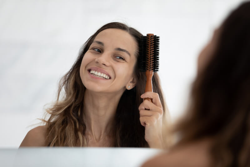 Head shot close up happy young woman brushing long dark hair