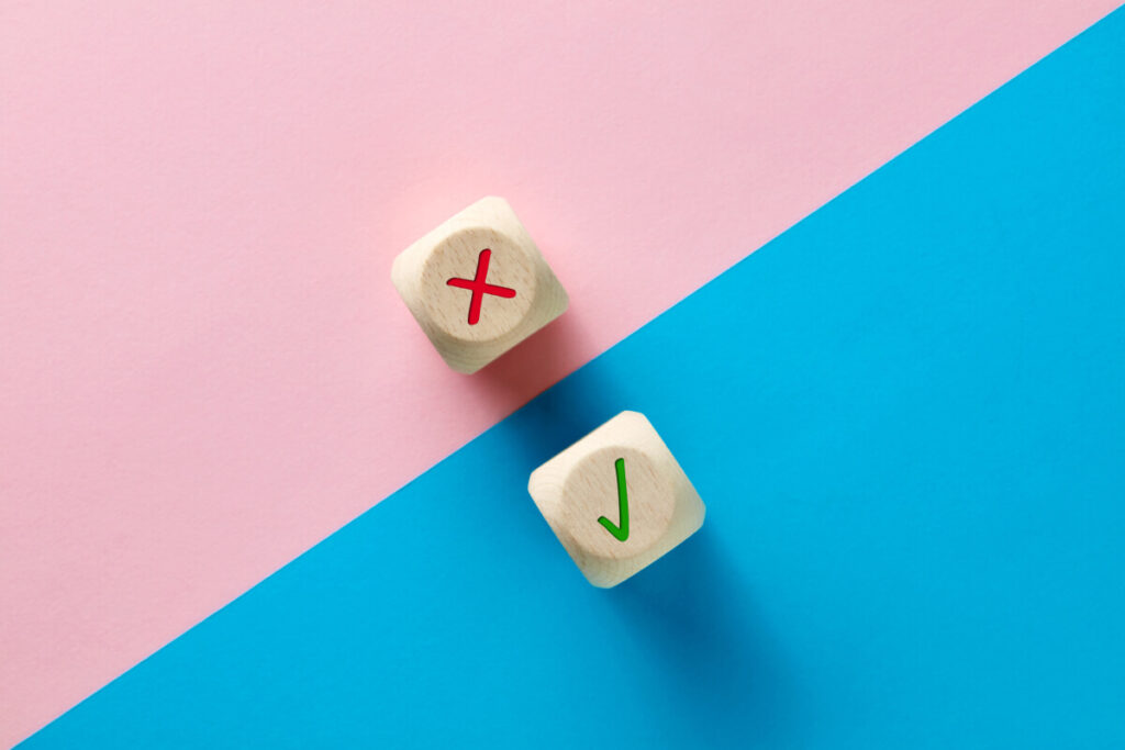 Wrong and right symbols on wooden cubes on pink and blue background