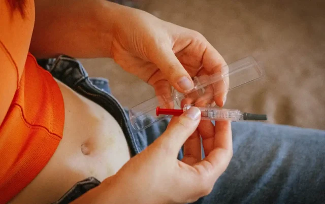a woman unwrap a syringe with hypodermic needle