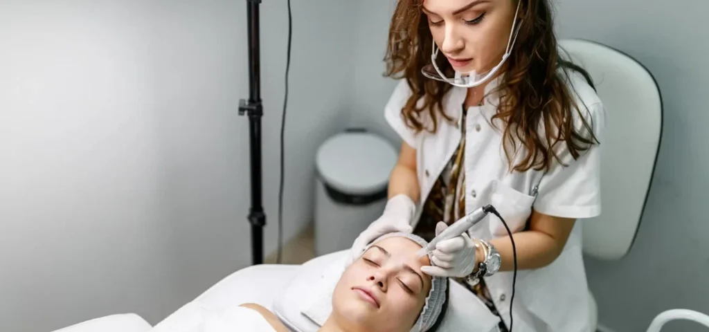 an aesthetician performs facial treatment procedure on her client.