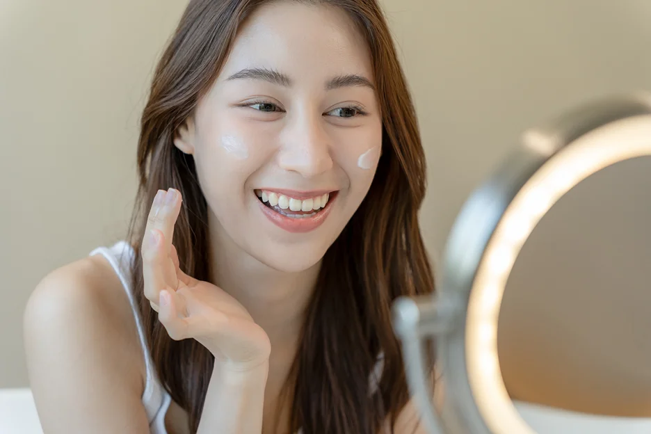 a woman applies moisturizer on her face after korean salmon dna injection treatment