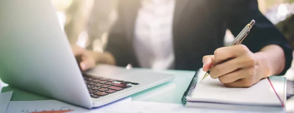 Woman in front of a laptop taking notes