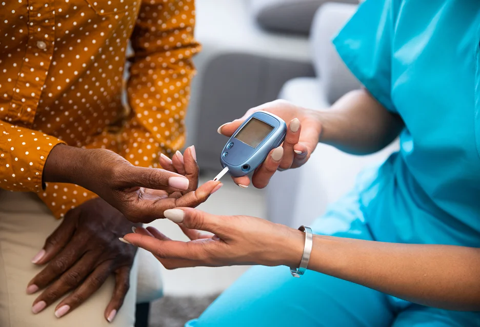 a nurse aids a female patient in checking the glucose level