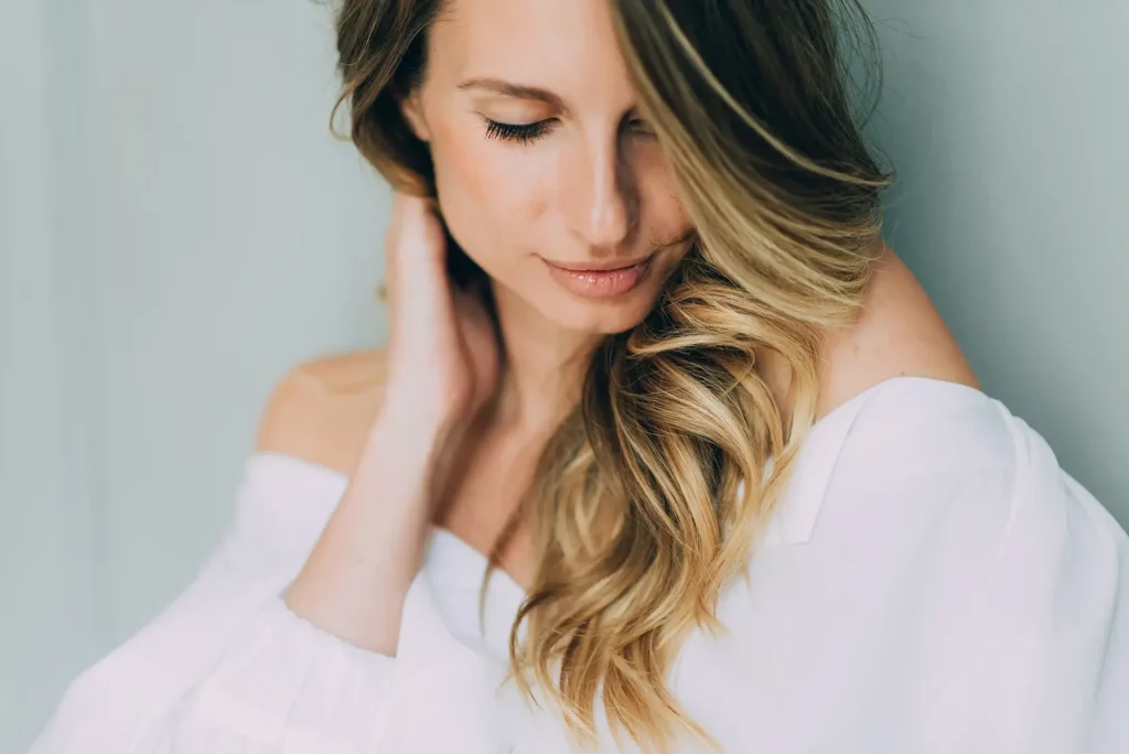 a portrait of a woman holding her fuller, wavy hair after exosomes treatment