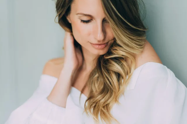 a portrait of a woman holding her fuller, wavy hair after exosomes treatment